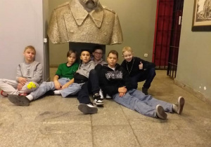 Uczniowie siedzą pod pomnikiem Józefa Piłsudskiego