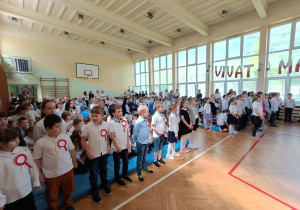 Uczniowie ubrani na galowo stoją i śpiewają