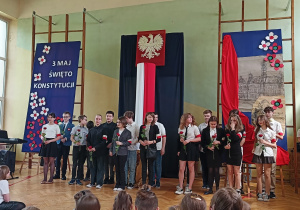 Uczniowie śpiewają, trzymając róże