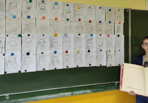 Uczeń stoi przy tablicy i trzyma książkę