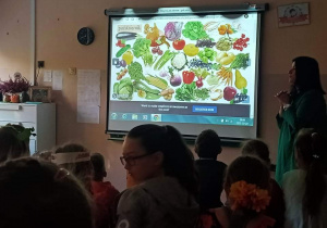 Uczniowie oglądaja prezentację o warzywach i owocach.
